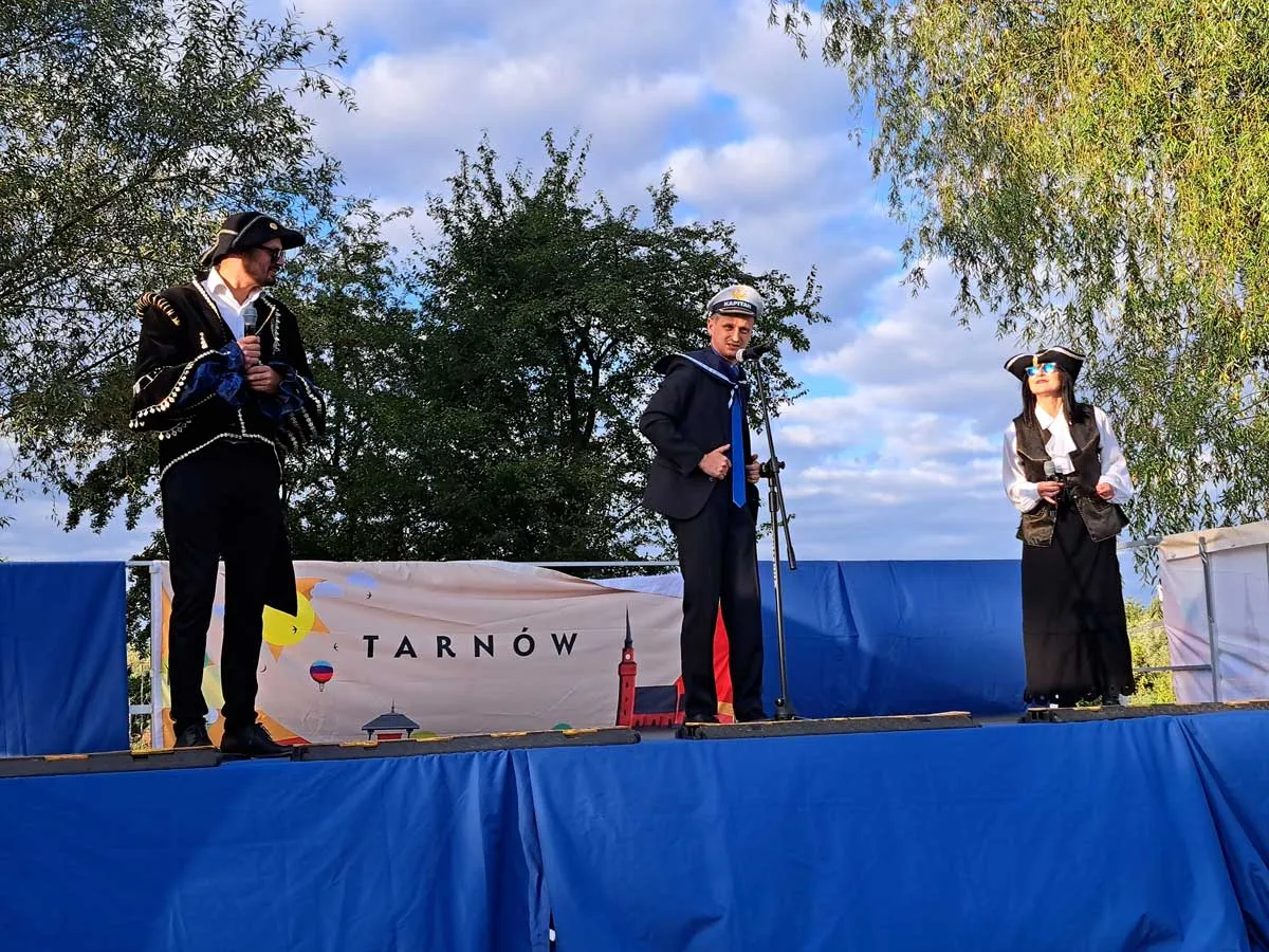 Wykonawcy w strojach marynarskich i pirackich na scenie z banerem Tarnów podczas koncertu szant